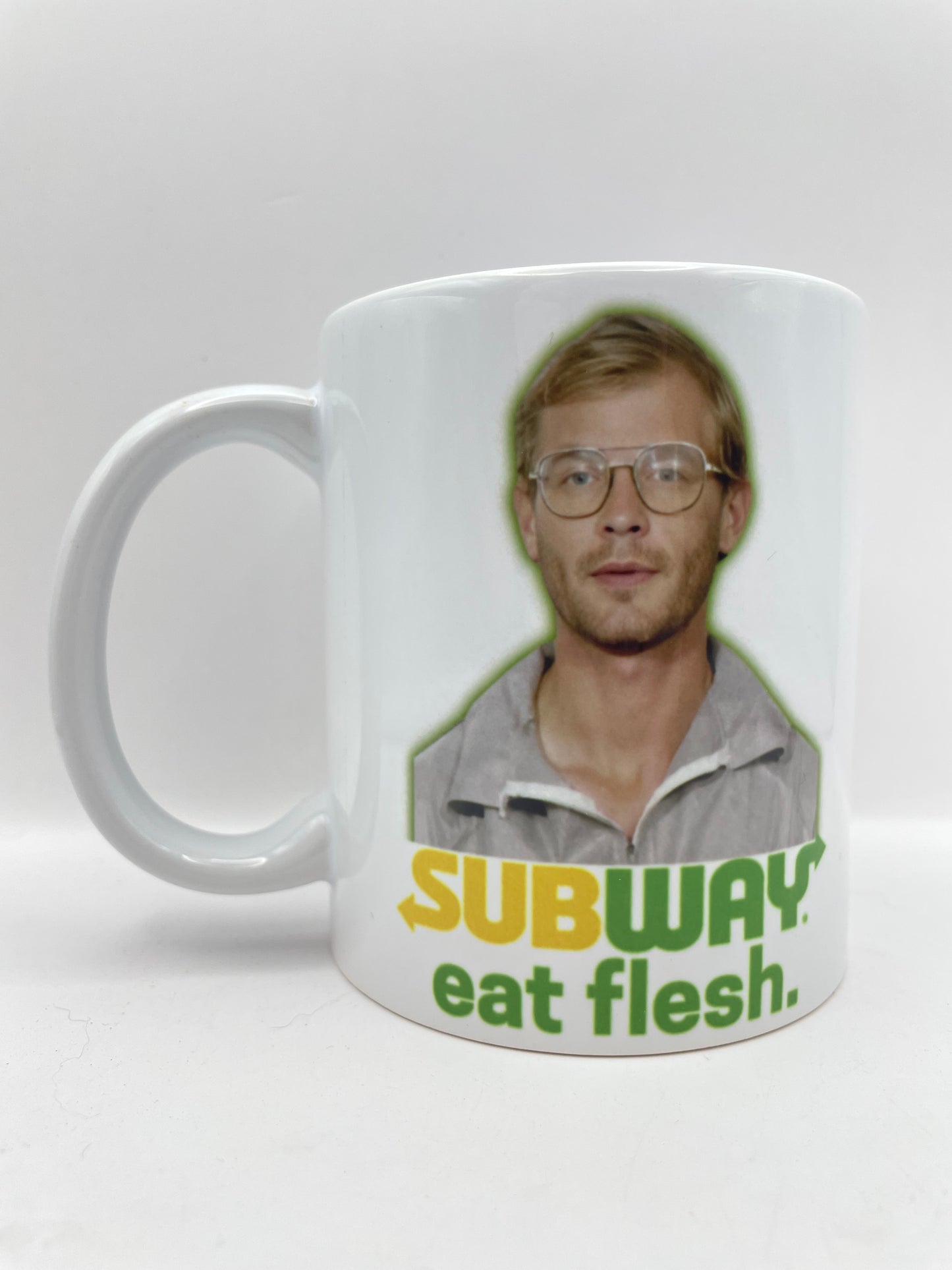 Mug with a graphic of a person and text 'SUBWAY eat flesh' on a white background